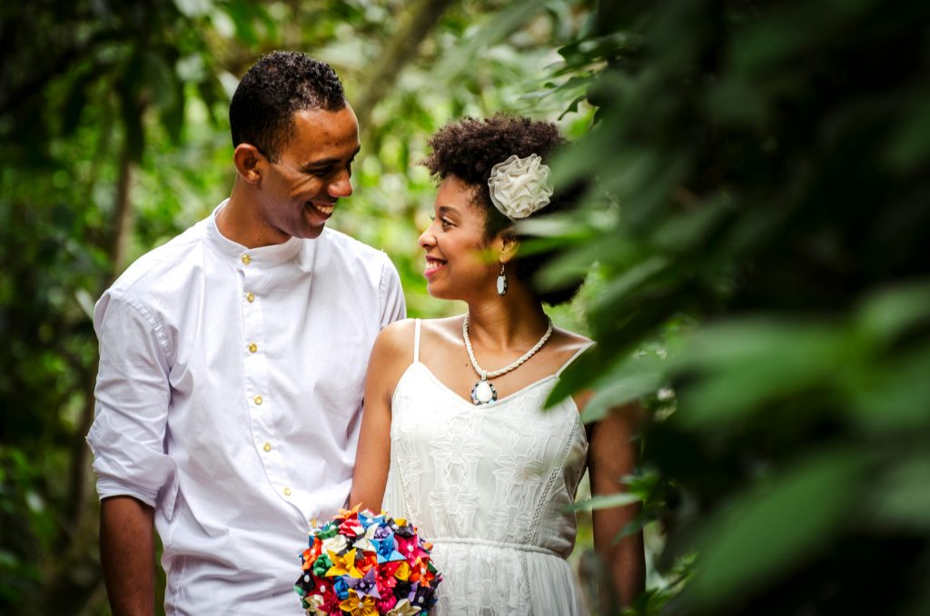 Happy African couple in wedding attire sharing a joyful moment outdoors.